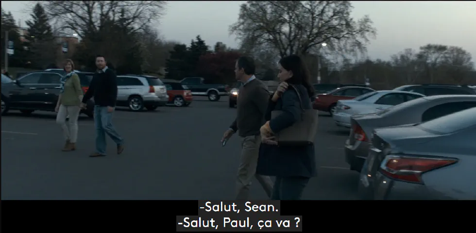 Quatre personnes marchent sur un parking extérieur. Le sous-titre indique : « -Salut, Sean. -Salut, Paul, ça va ? ».